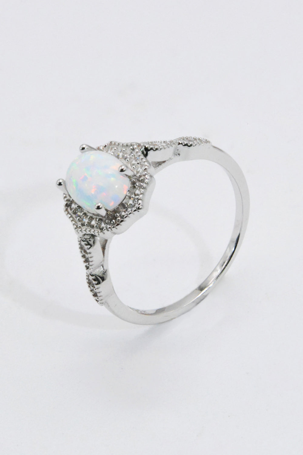 Close-up of oval opal with iridescent color play, framed by pavé halo