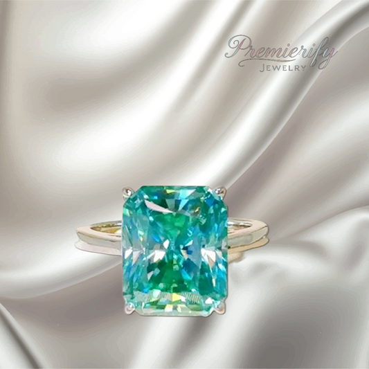 Ring with a large green gemstone on a silver satin background, featuring the brand 'Premierify Jewelry'.