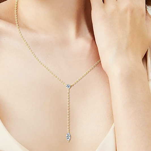 Gold necklace with a clear gemstone worn by a person