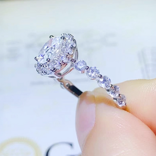 Close-up of a diamond ring held between fingers with a blurred background