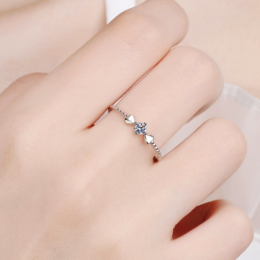 Silver ring with a heart-shaped gemstone on a finger