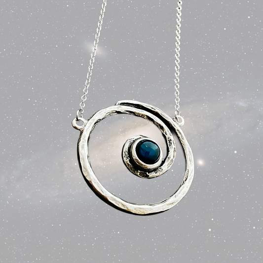 Silver necklace with a circular pendant featuring a blue gemstone on a gray background