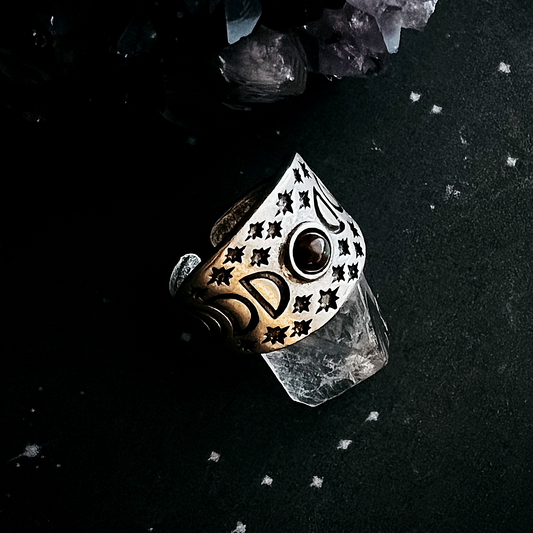 Decorative ring with star patterns on a dark surface with crystals