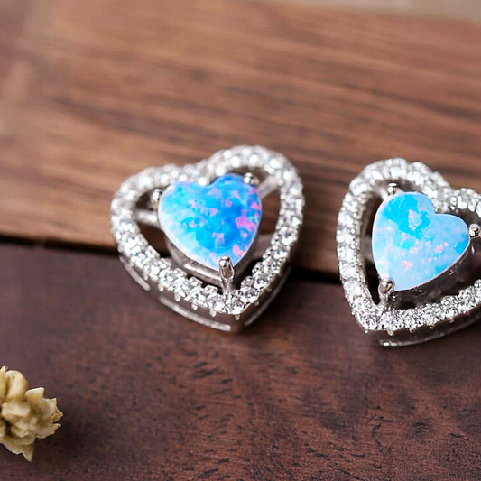 Heart-shaped earrings with blue gemstones on a wooden surface