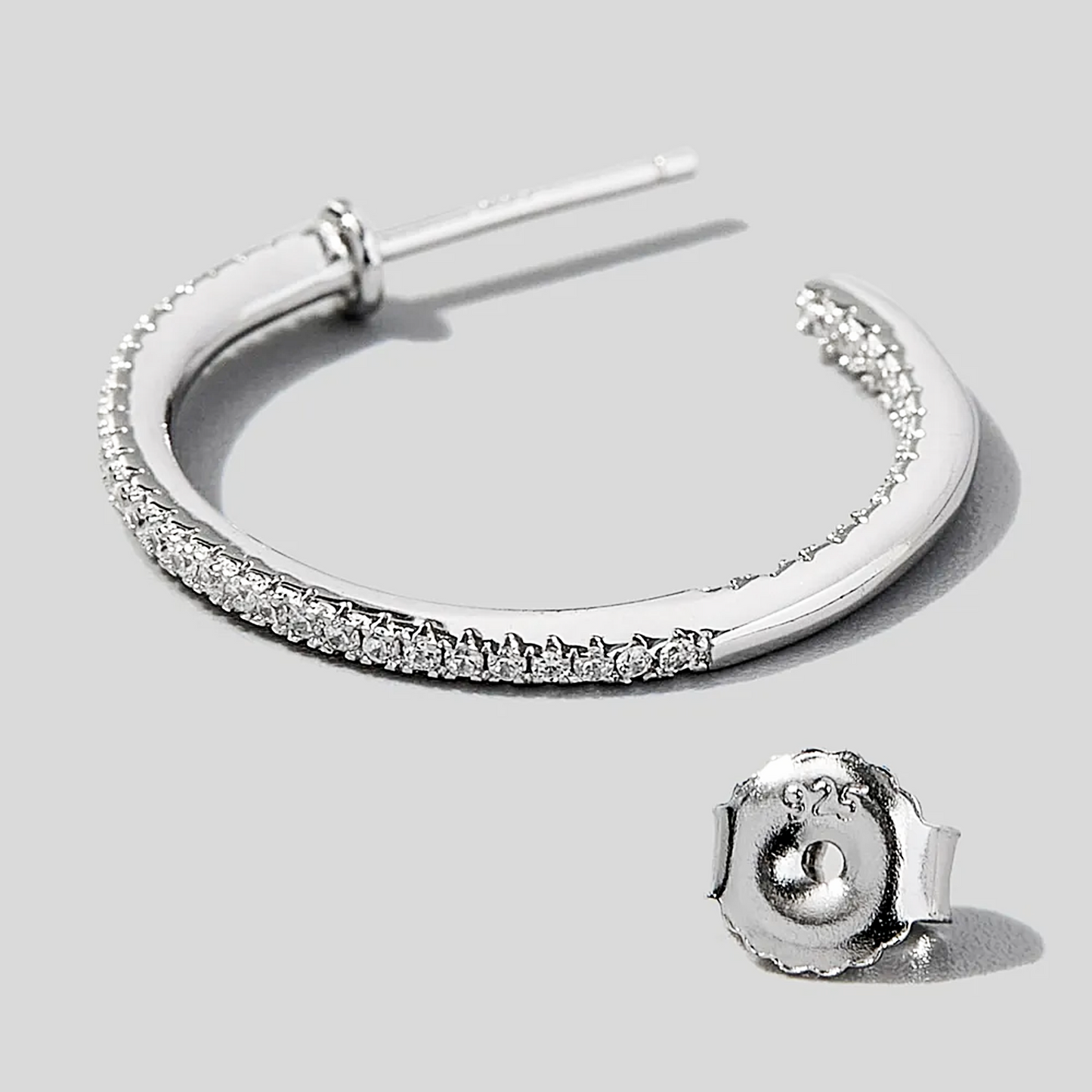 Silver hoop earring with clear gemstones on a light gray background