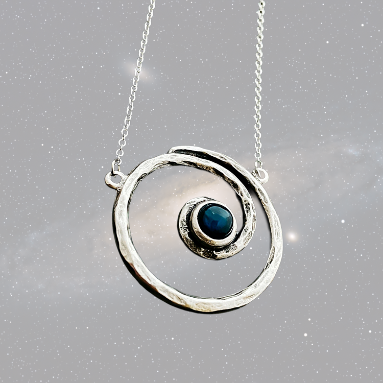 Spiral silver pendant with blue stone center on a starry background