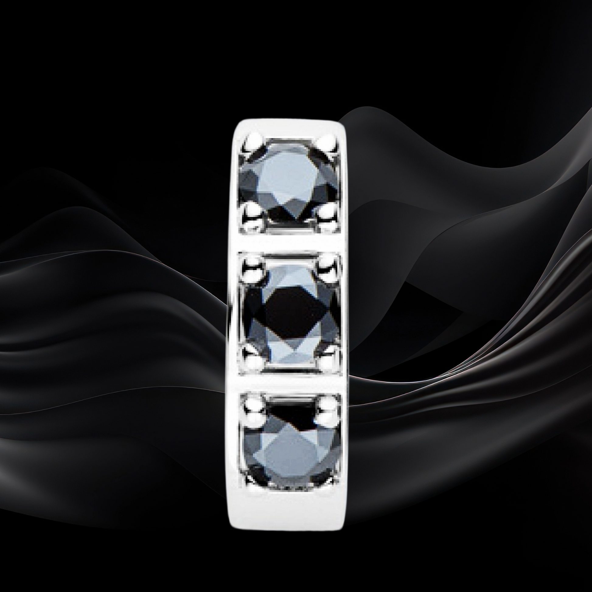 Silver ring with three blue gemstones on a black fabric background