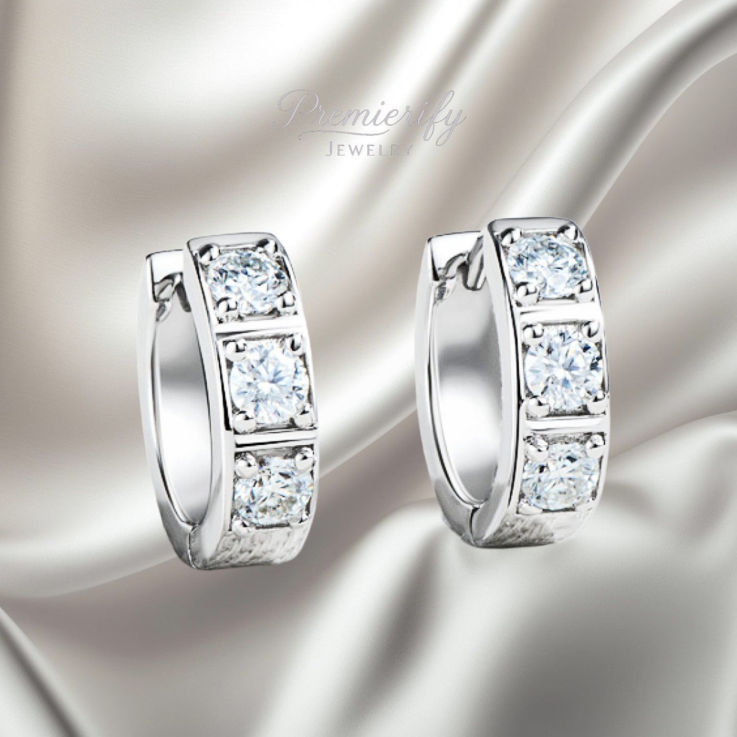 Pair of silver hoop earrings with clear gemstones on a satin surface, branded 'Premier Jewelry'.