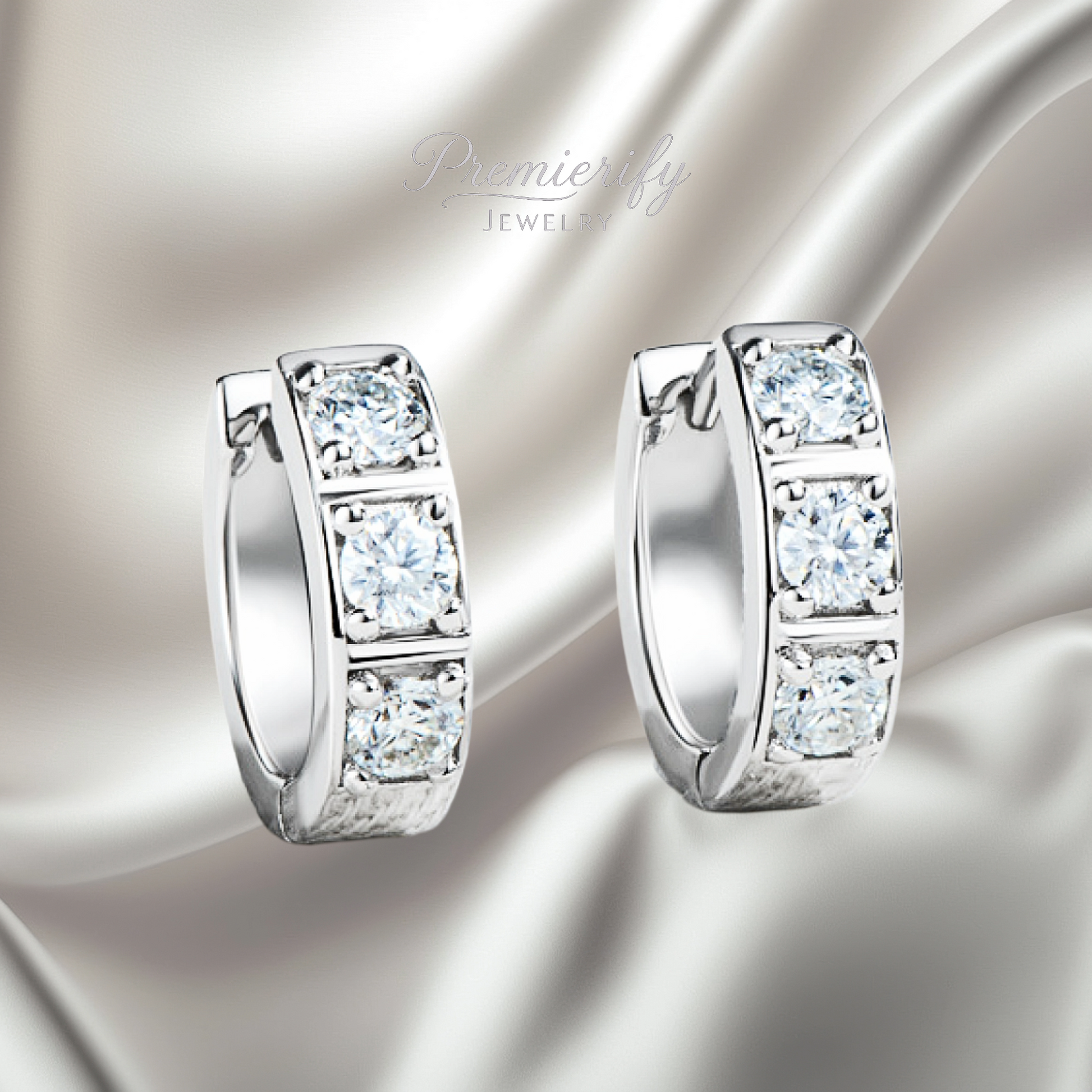 Pair of silver hoop earrings with clear gemstones on a satin surface, branded 'Premier Jewelry'.