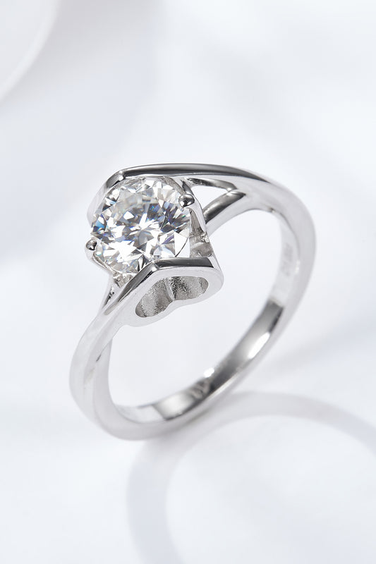 Three-quarter close-up of a 1 ct round-cut moissanite solitaire ring in platinum-plated sterling on black satin, showing facets and a slim band