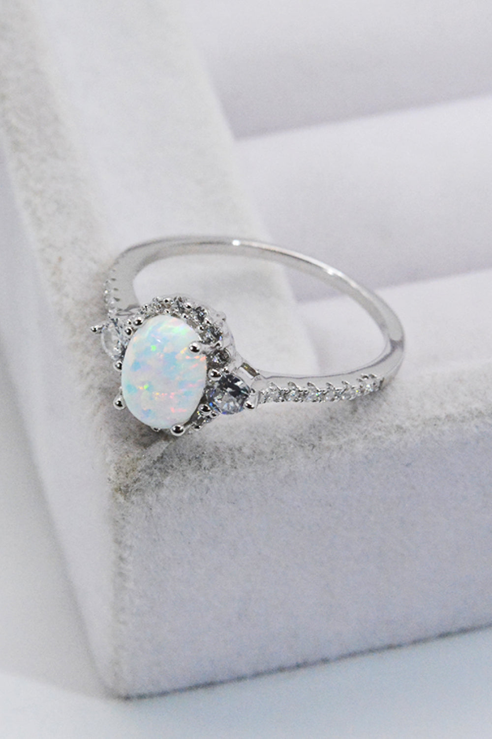 Close-up of oval opal with iridescent color play, framed by pavé halo