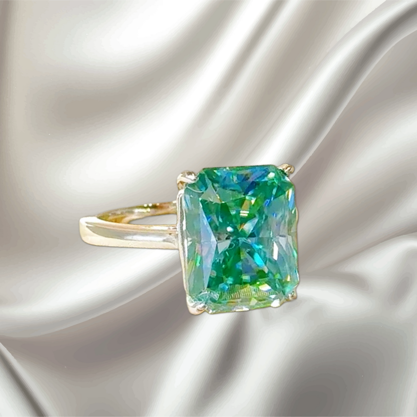 Gold ring with a large green gemstone on a satin background