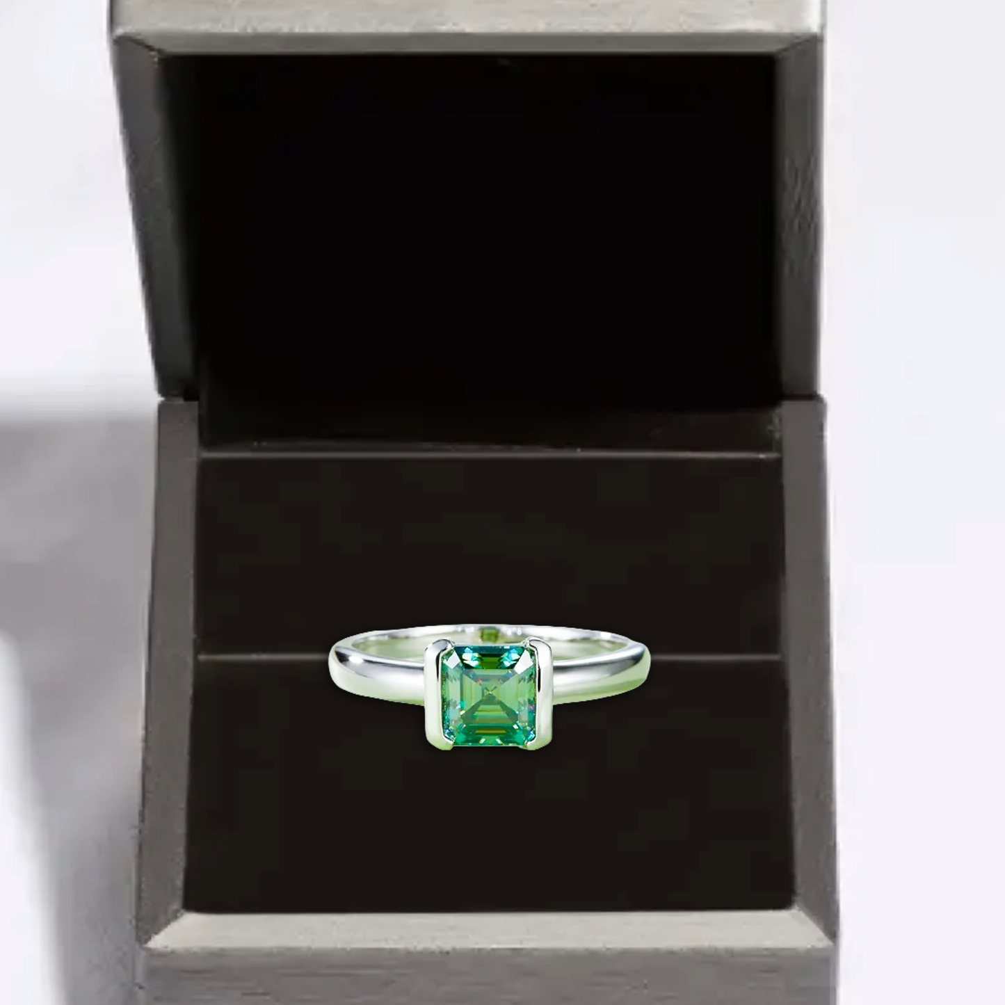 Silver ring with a green gemstone in a black box