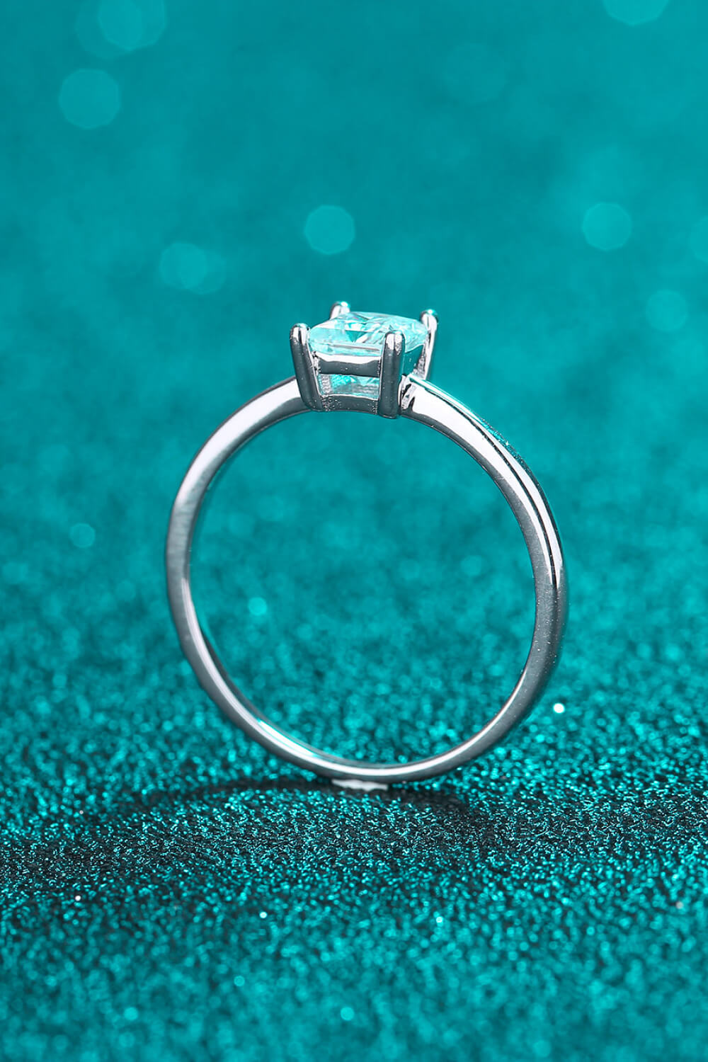 Auren orincess cut ring on teal background.