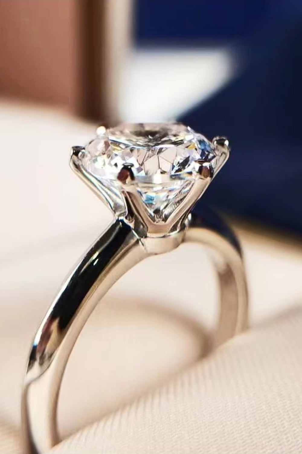Premierify™ Kaitlyn Ann 3 carat moissanite solitaire ring in platinum-plated 925 sterling silver – close-up sparkle over blush backdrop