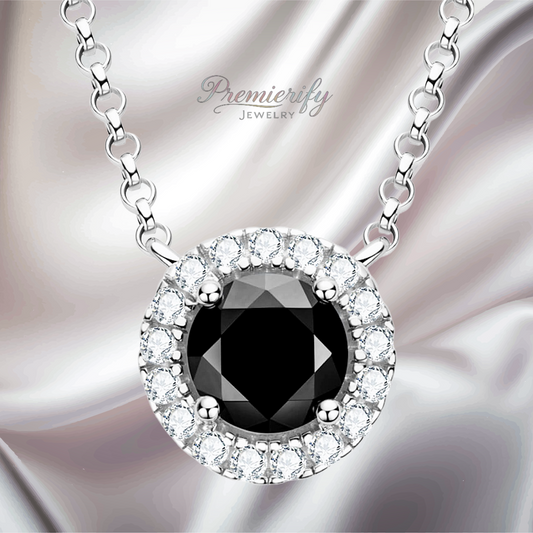 Black diamond pendant necklace with white stones on a silver chain against a soft fabric background.