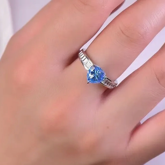Ring with a blue gemstone on a finger against a white background