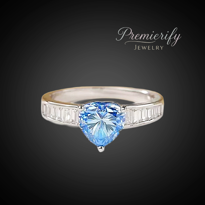 Silver ring with a heart-shaped blue gemstone on a dark background, featuring the 'Premierify Jewelry' logo.