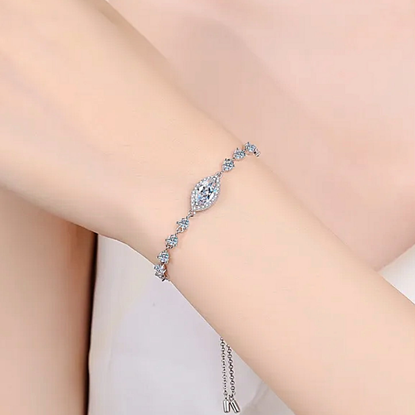 Silver bracelet with clear stones on a wrist against a light background