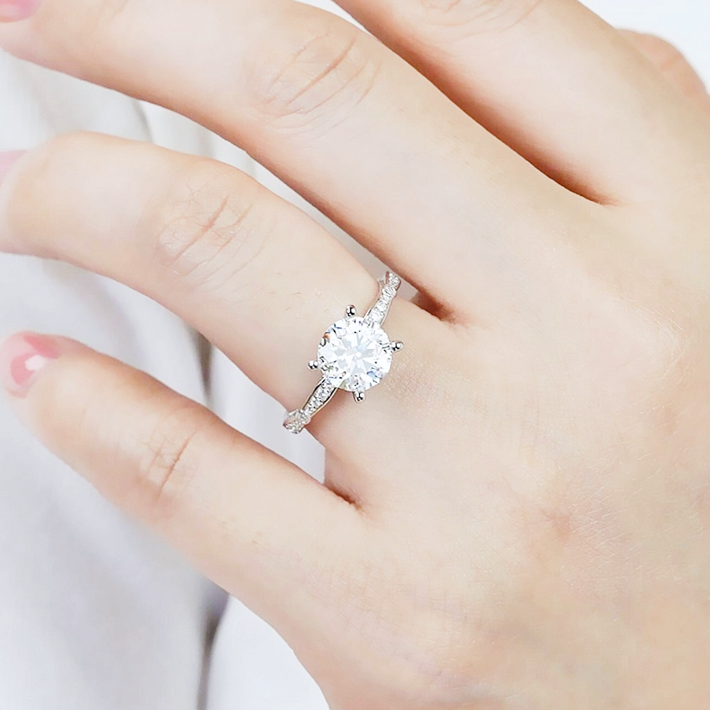 Silver ring with a large diamond on a hand against a white background