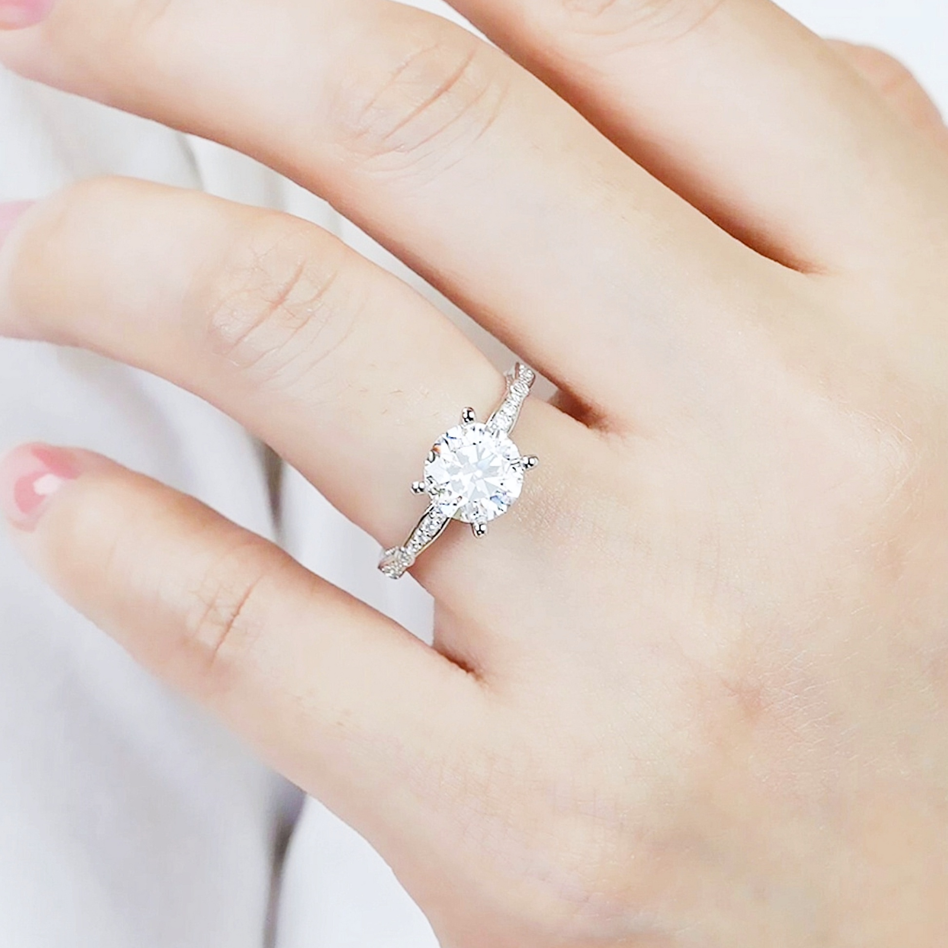 Silver ring with a large diamond on a hand against a white background