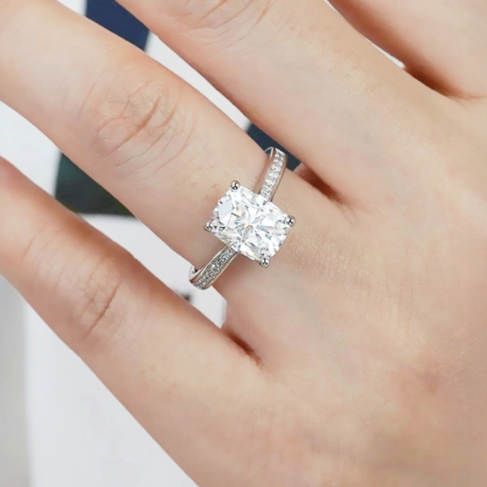 Silver ring with a large diamond on a hand against a neutral background