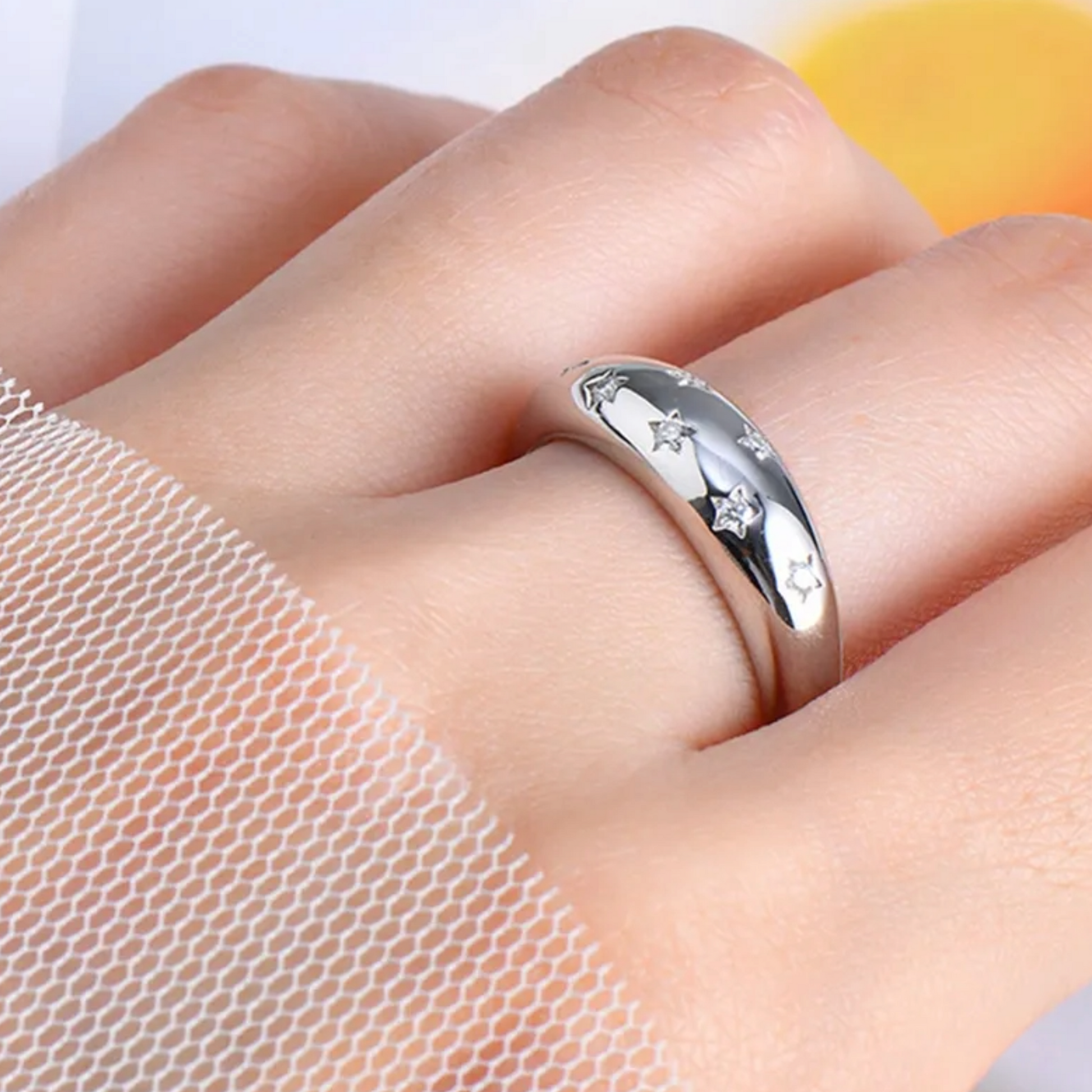 Silver ring with star designs on a person's finger