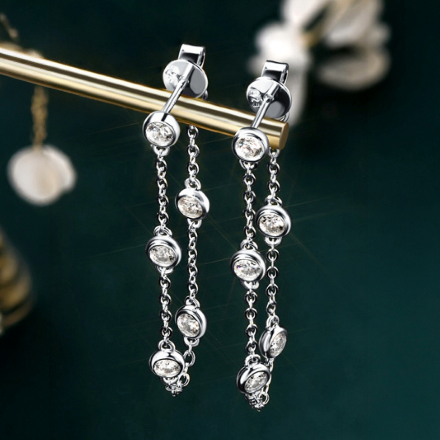 Silver chain earrings with clear stones on a dark background