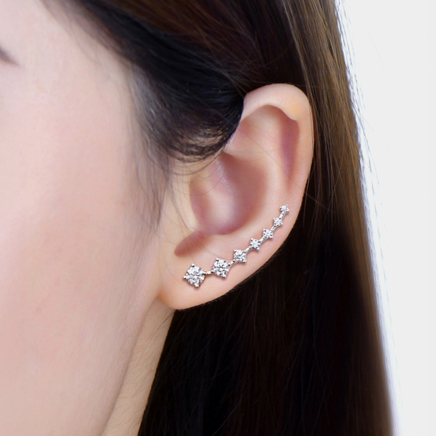 Close-up of an ear wearing a silver earring with small diamonds.