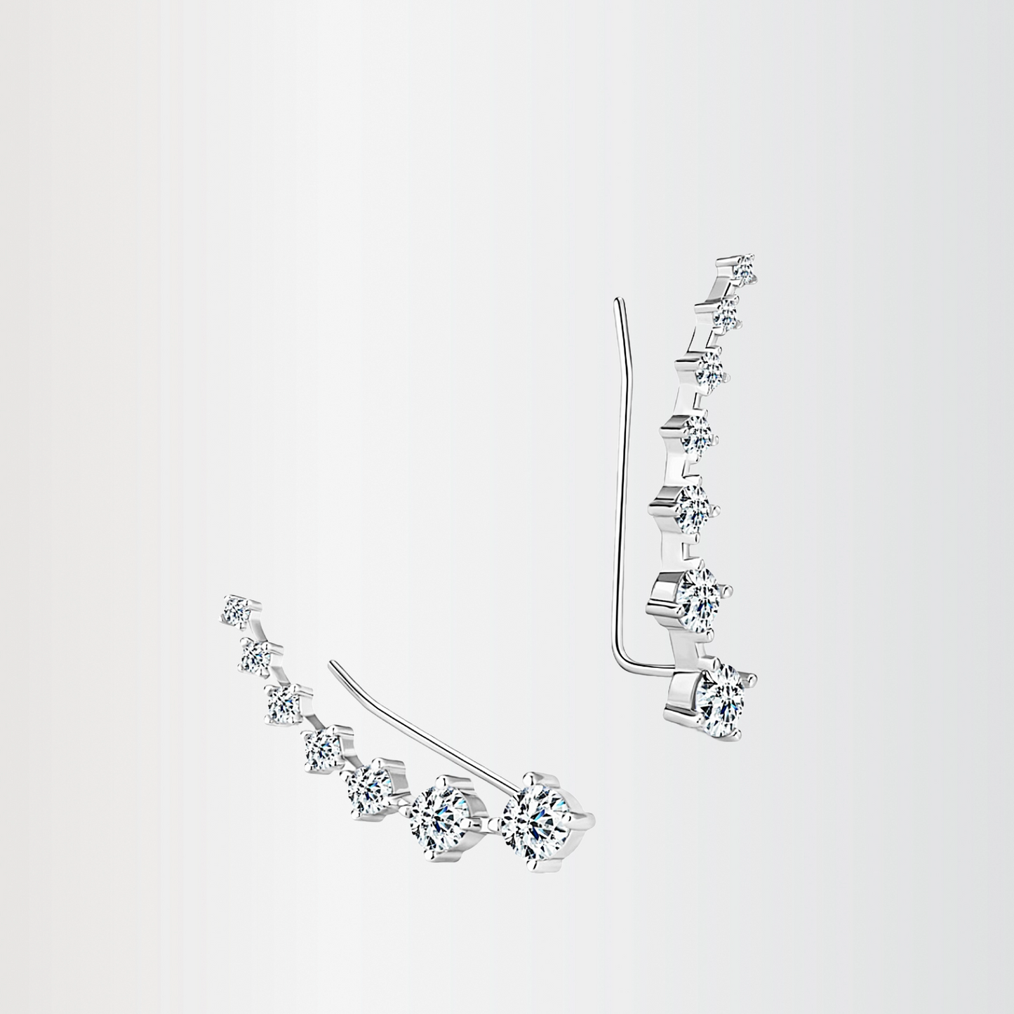 Pair of silver earrings with clear gemstones on a light gray background