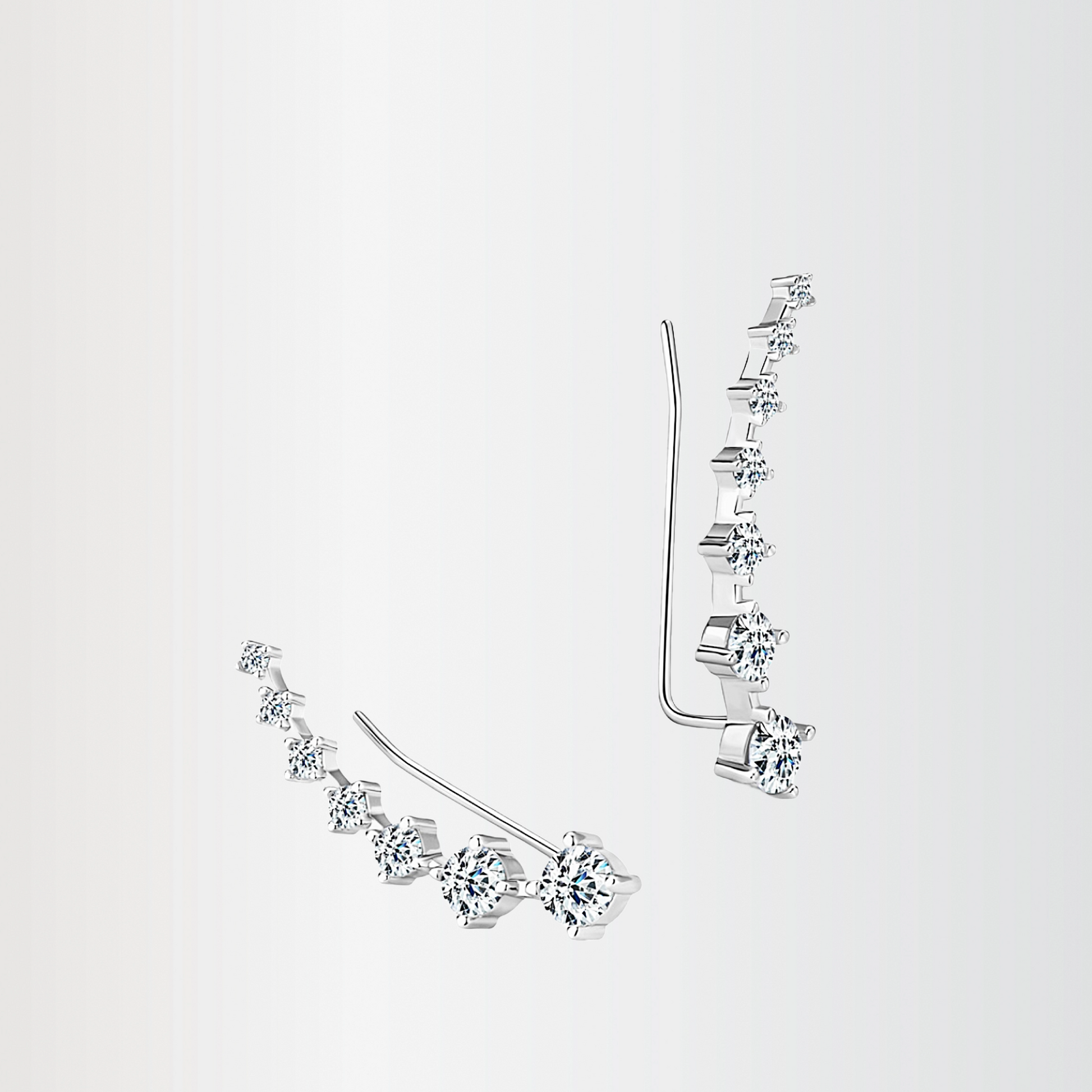 Pair of silver earrings with clear gemstones on a light gray background