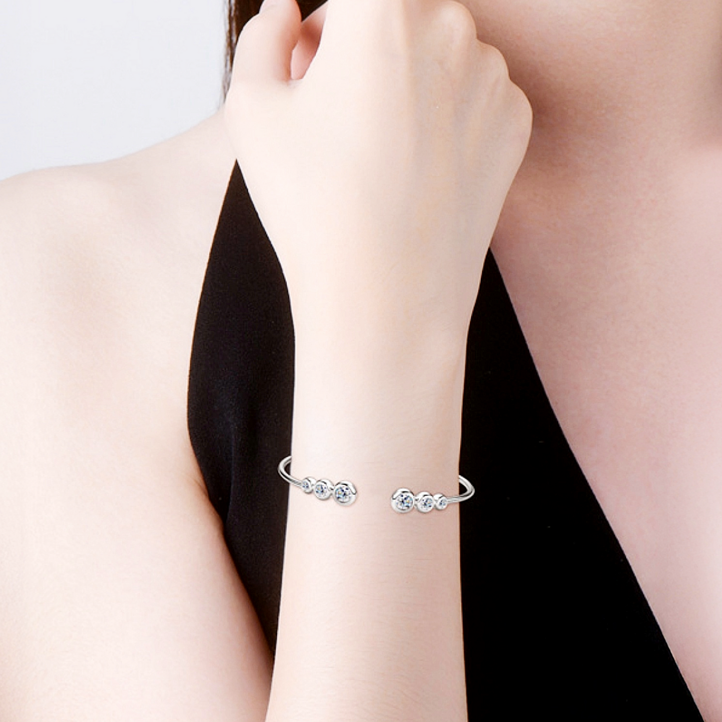 Silver bracelet on a person's wrist with a plain background