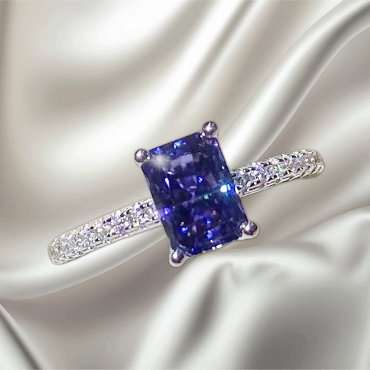 Blue gemstone ring with diamond accents on a satin background