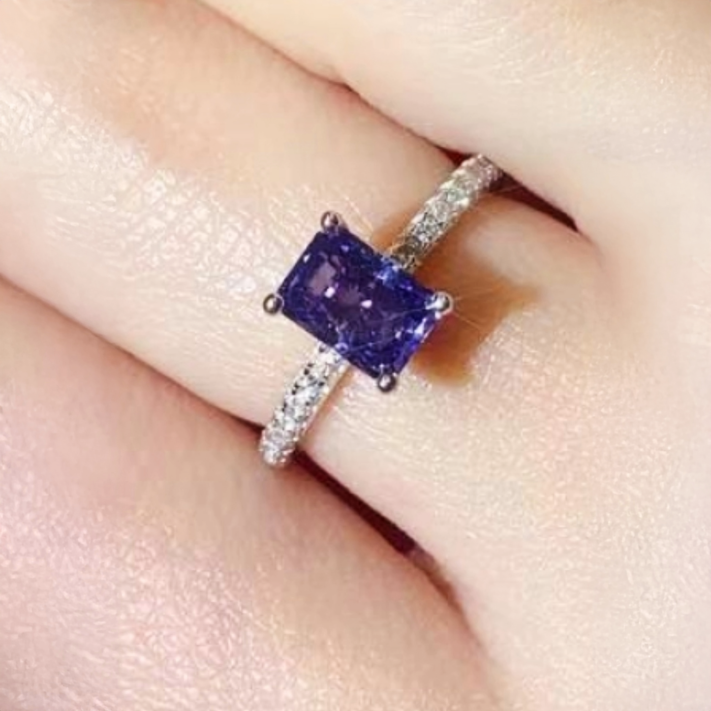 Ring with a purple gemstone on a finger
