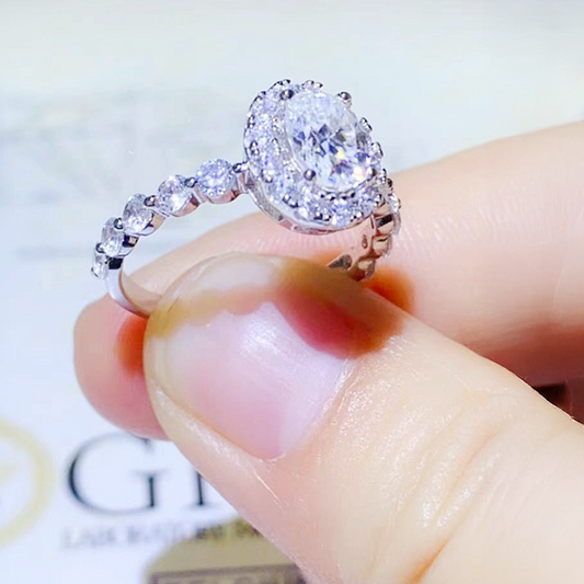 Close-up of a diamond ring held between fingers with a blurred background