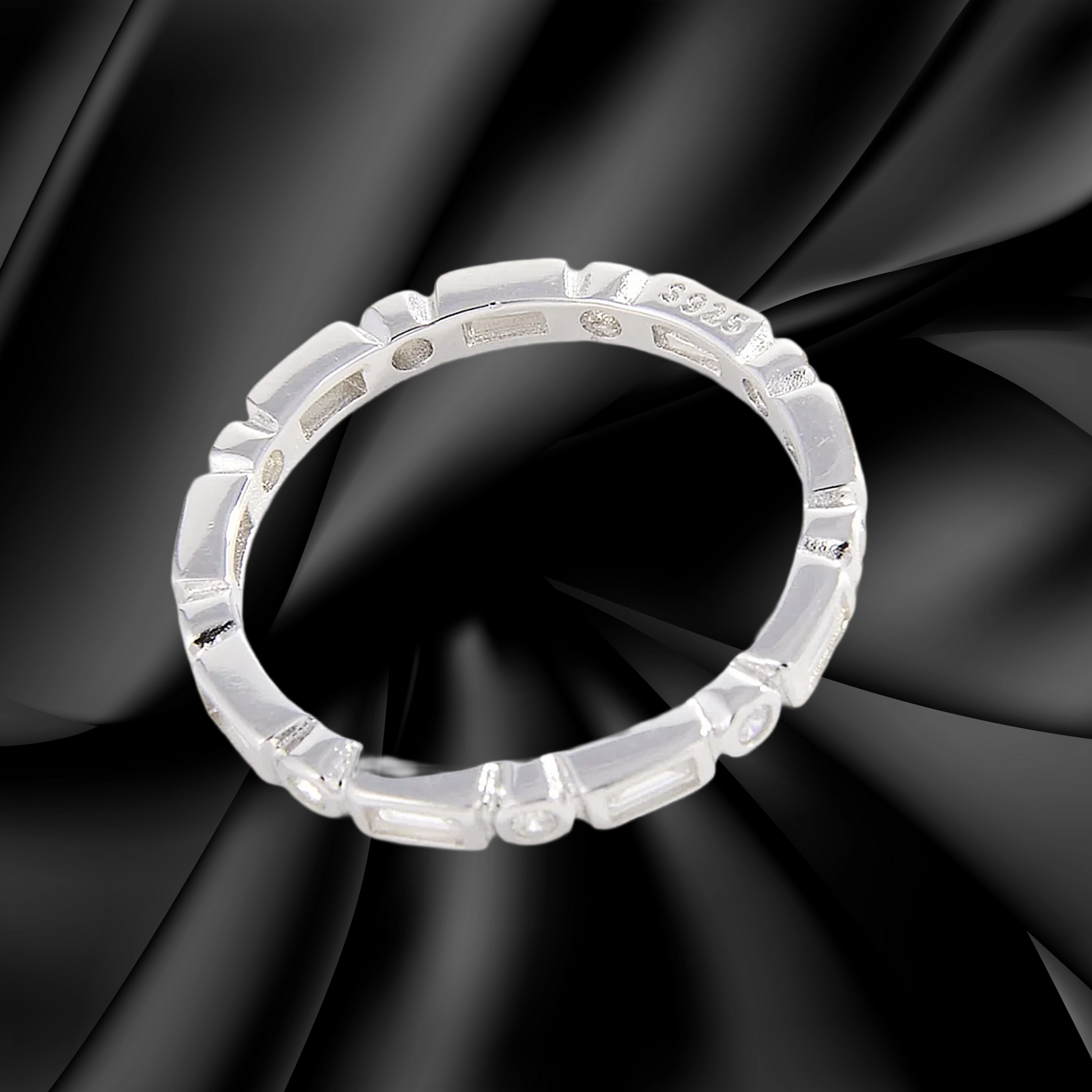 Silver ring with intricate design on a black fabric background