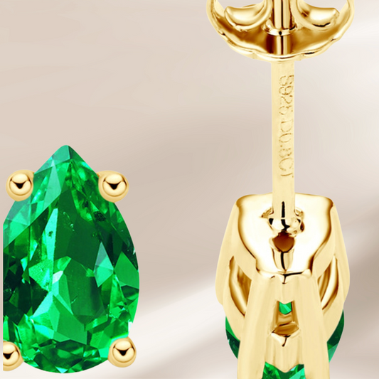 Gold earring with green gemstone on a beige background