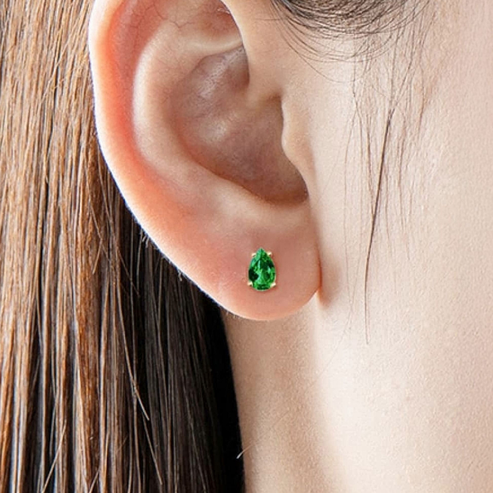 Close-up of an ear wearing a green gemstone earring.