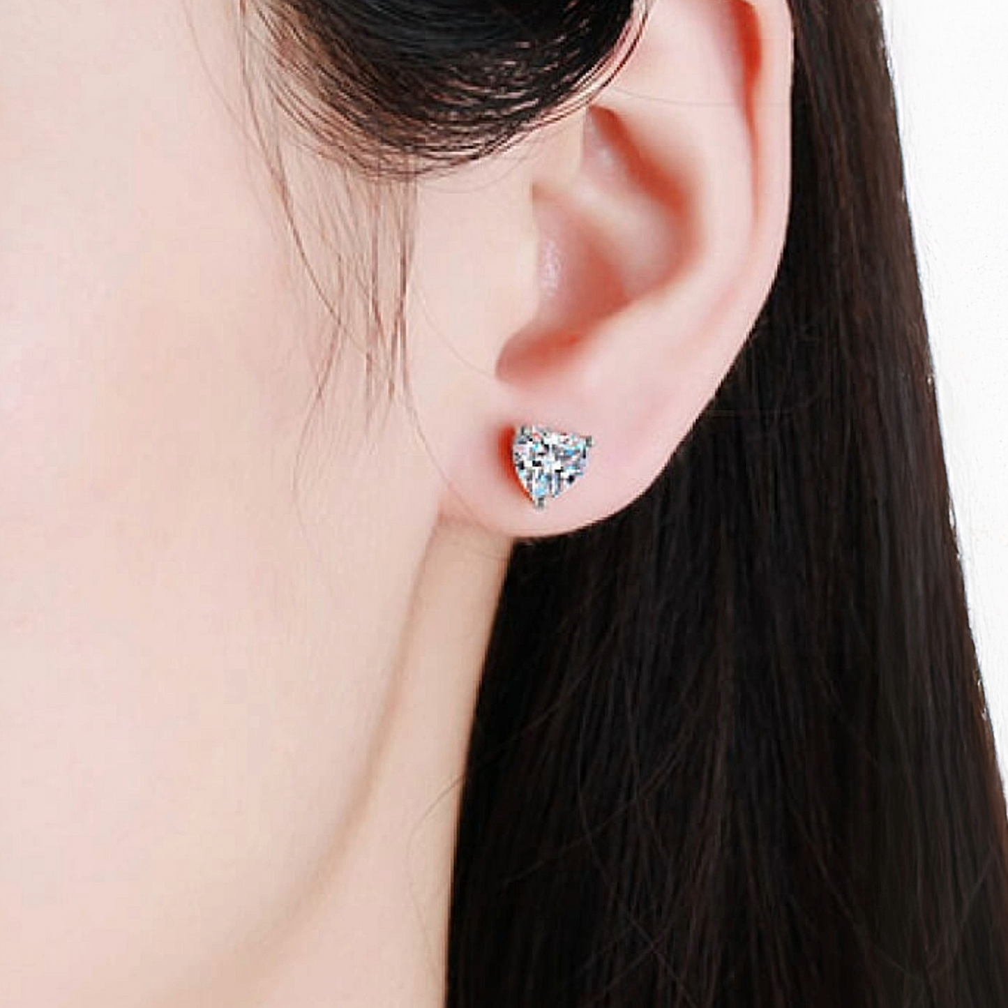Heart-shaped stud earring worn by a person with dark hair.