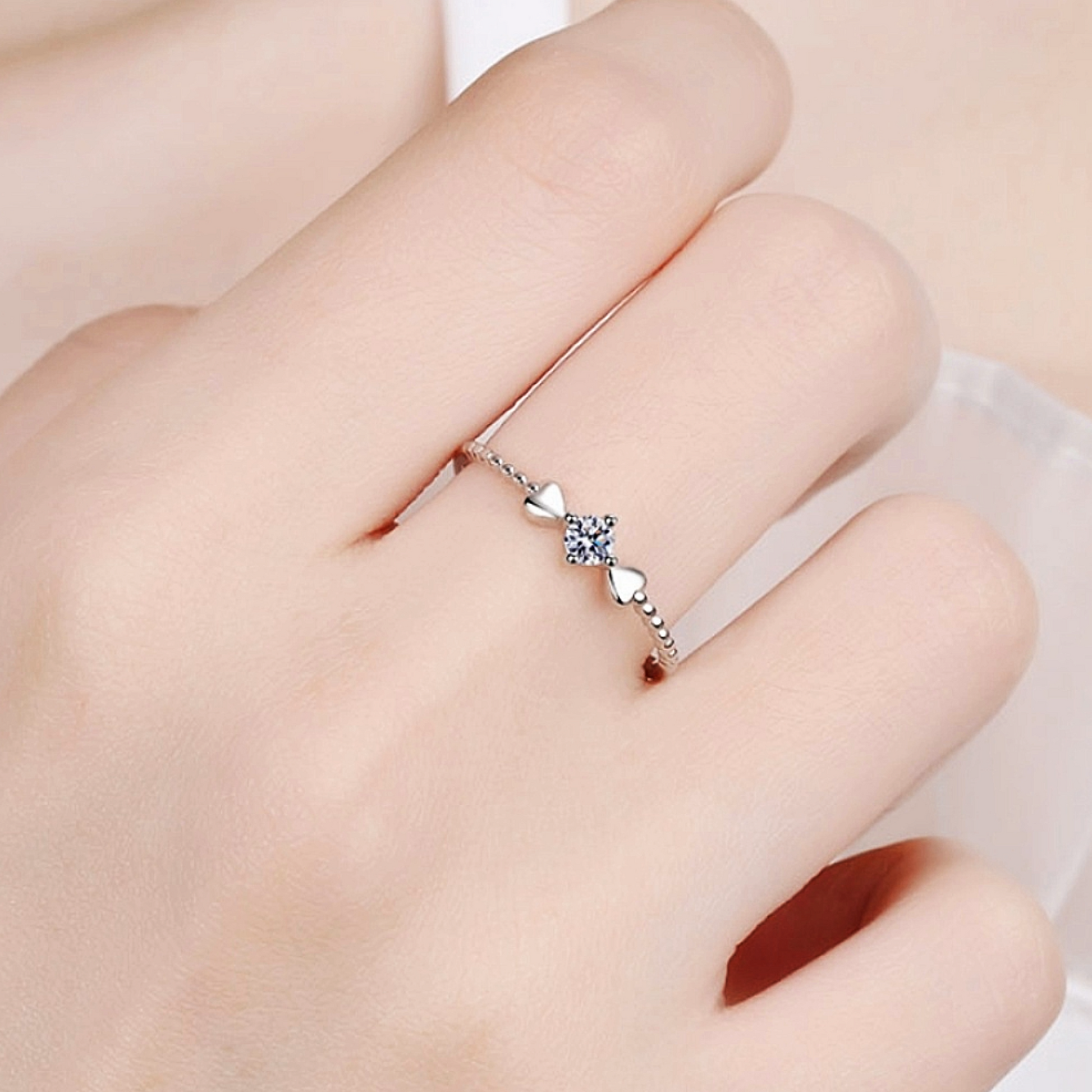 Silver ring with a heart-shaped gemstone on a finger