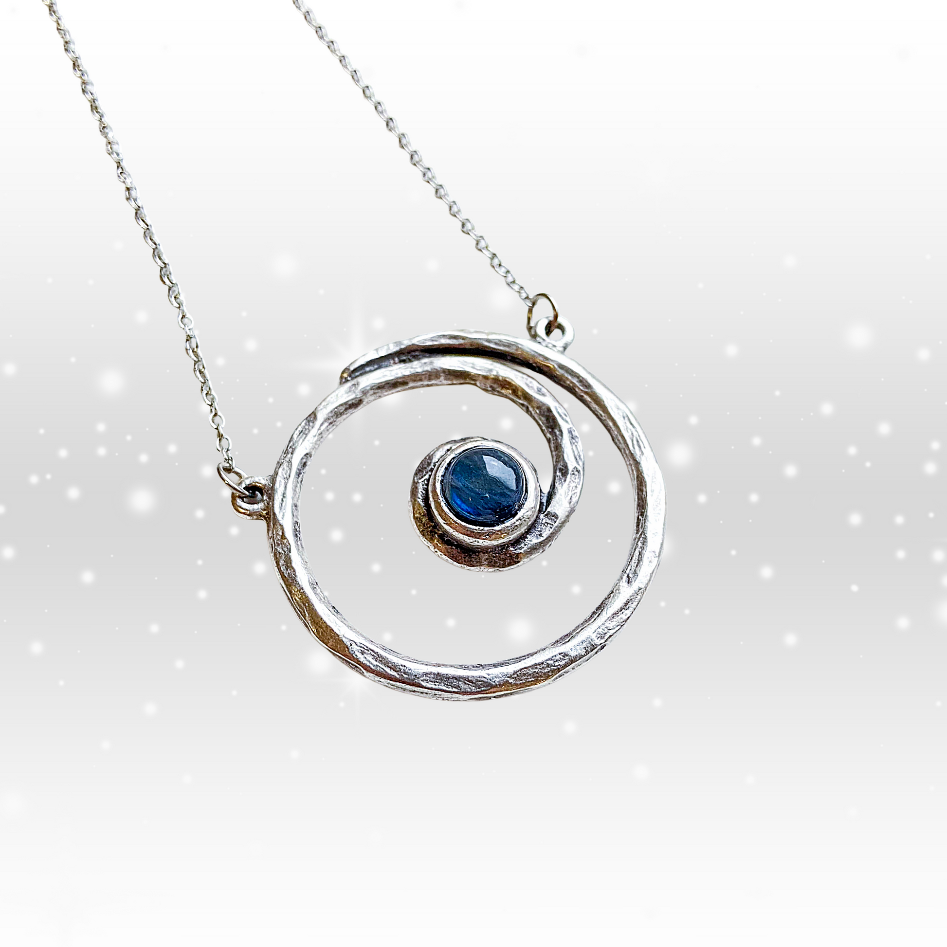 Silver necklace with a circular pendant featuring a blue gemstone on a white background