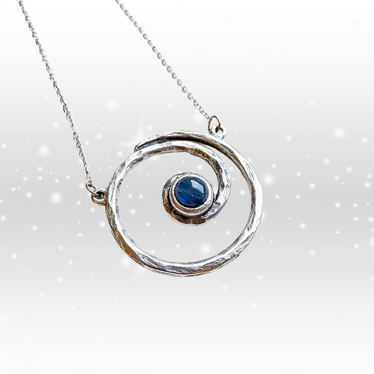 Silver necklace with a circular pendant featuring a blue gemstone on a white background
