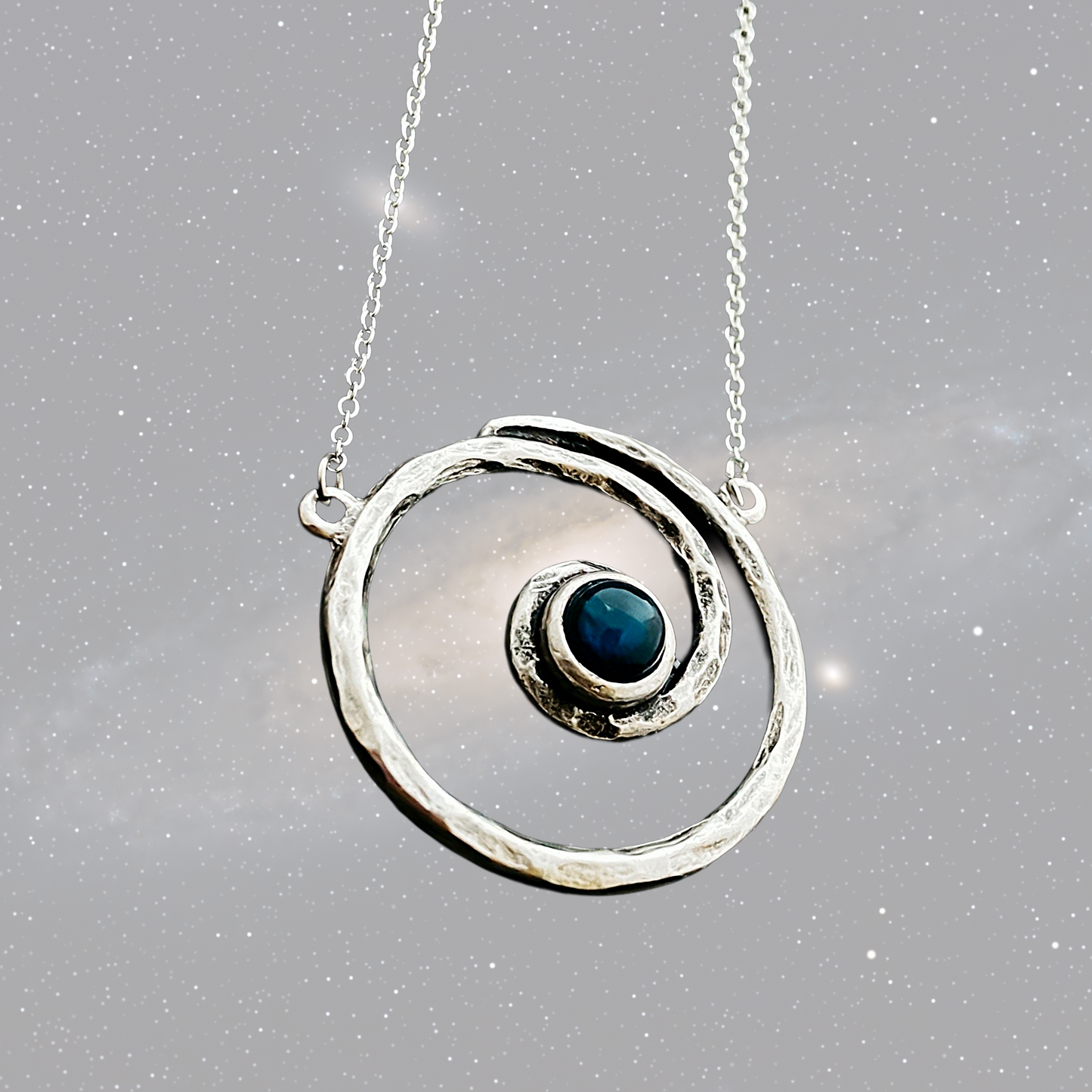 Silver necklace with a circular pendant featuring a blue gemstone on a gray background