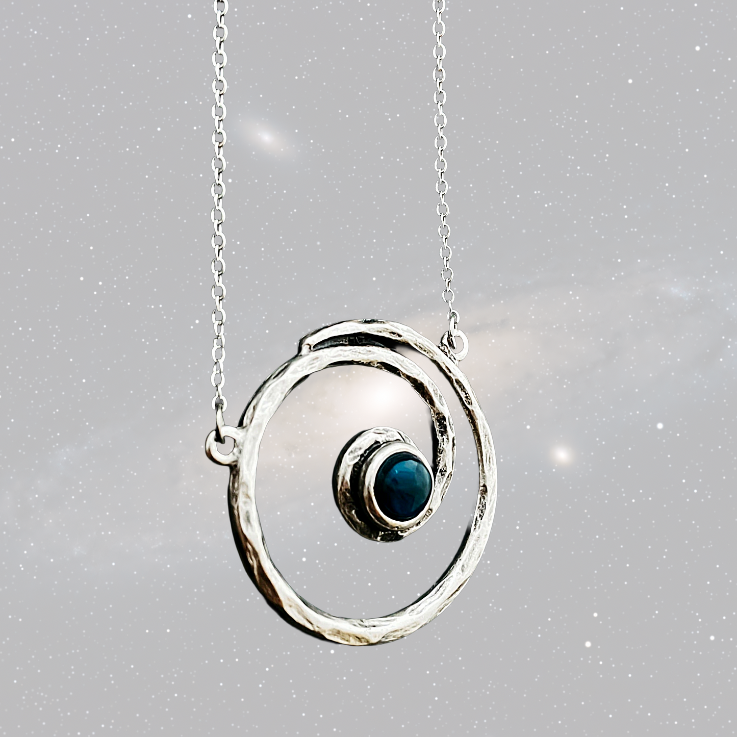 Silver necklace with a circular pendant featuring a blue gemstone on a gray background