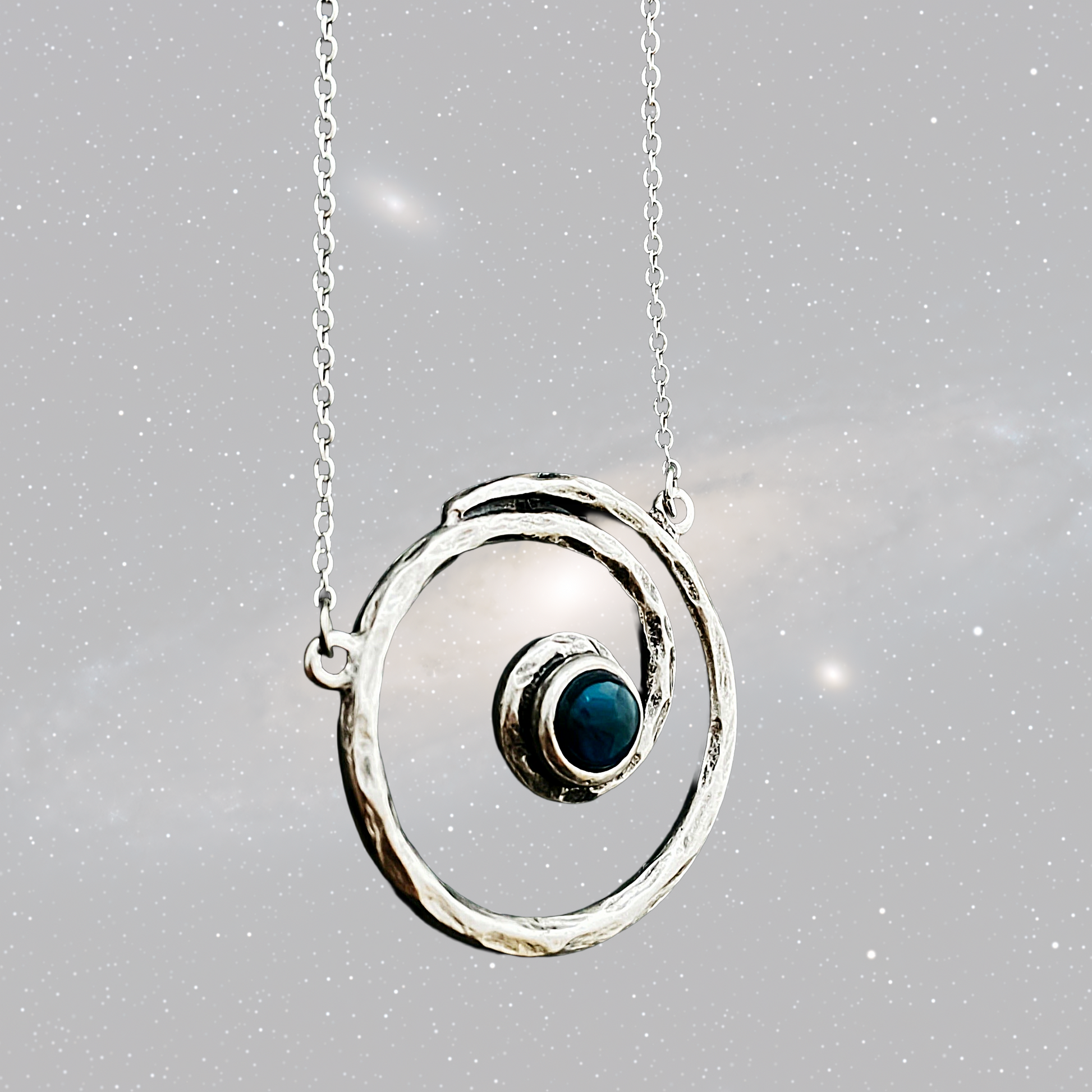 Silver necklace with a circular pendant featuring a blue gemstone on a gray background