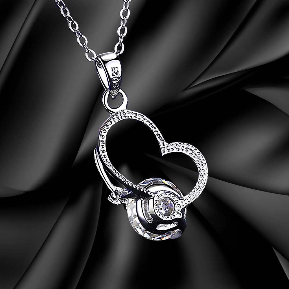 Silver heart-shaped pendant necklace on a black fabric background