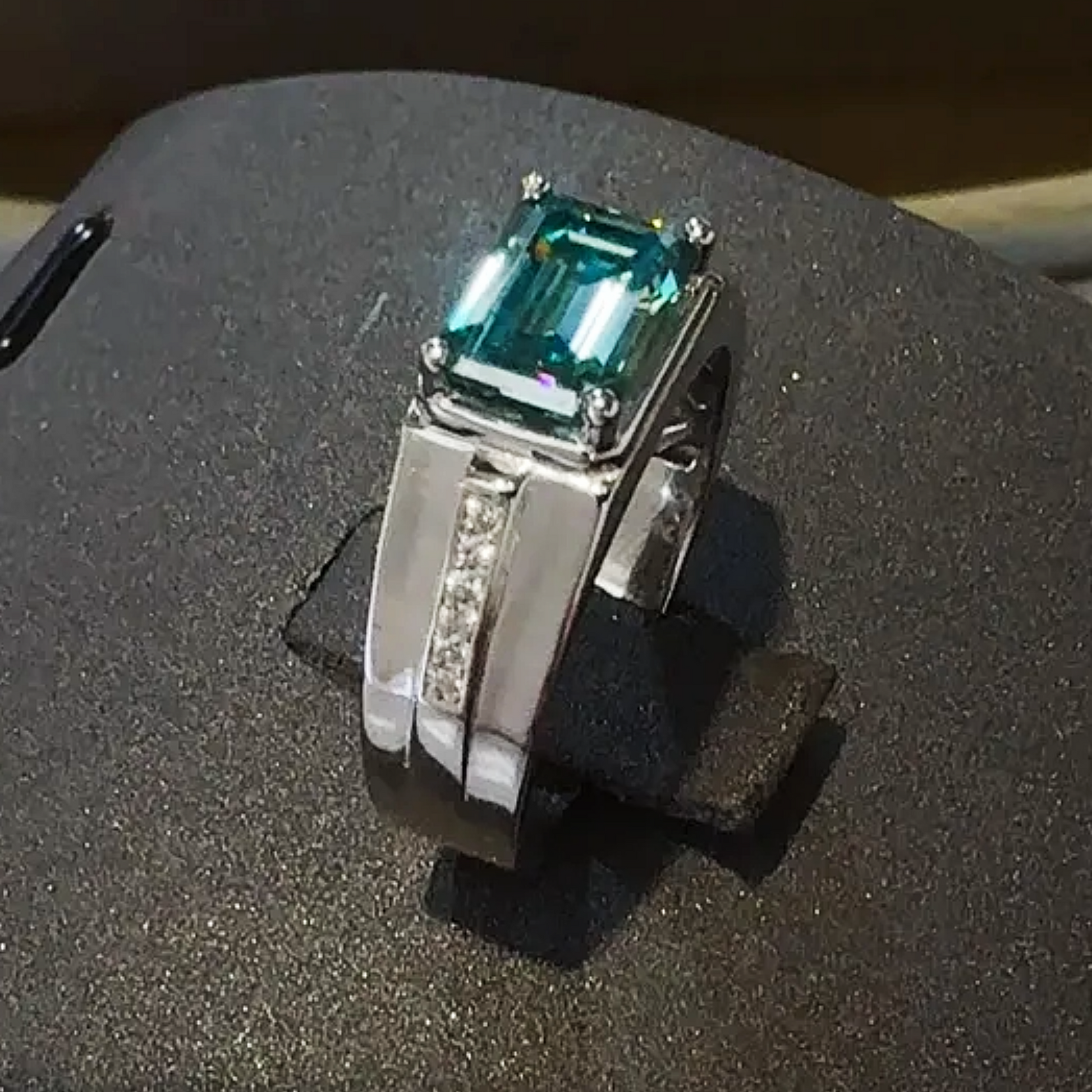 Silver ring with a green gemstone on a textured surface