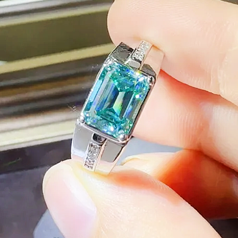 Silver ring with a large blue gemstone held between fingers.