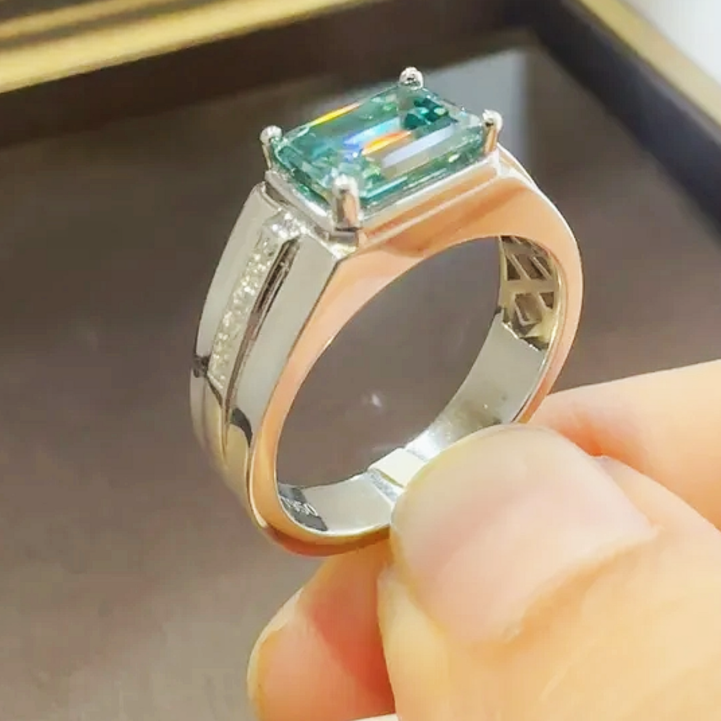 Gold ring with a green gemstone held by a hand