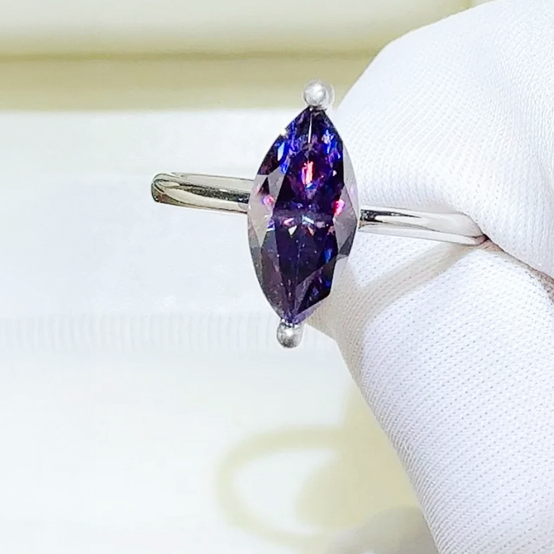 Ring with a marquise-shaped purple gemstone on a white background